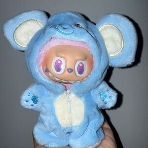 Adorable plush blue elephant outfit for Labubu with a blue carrying strap.